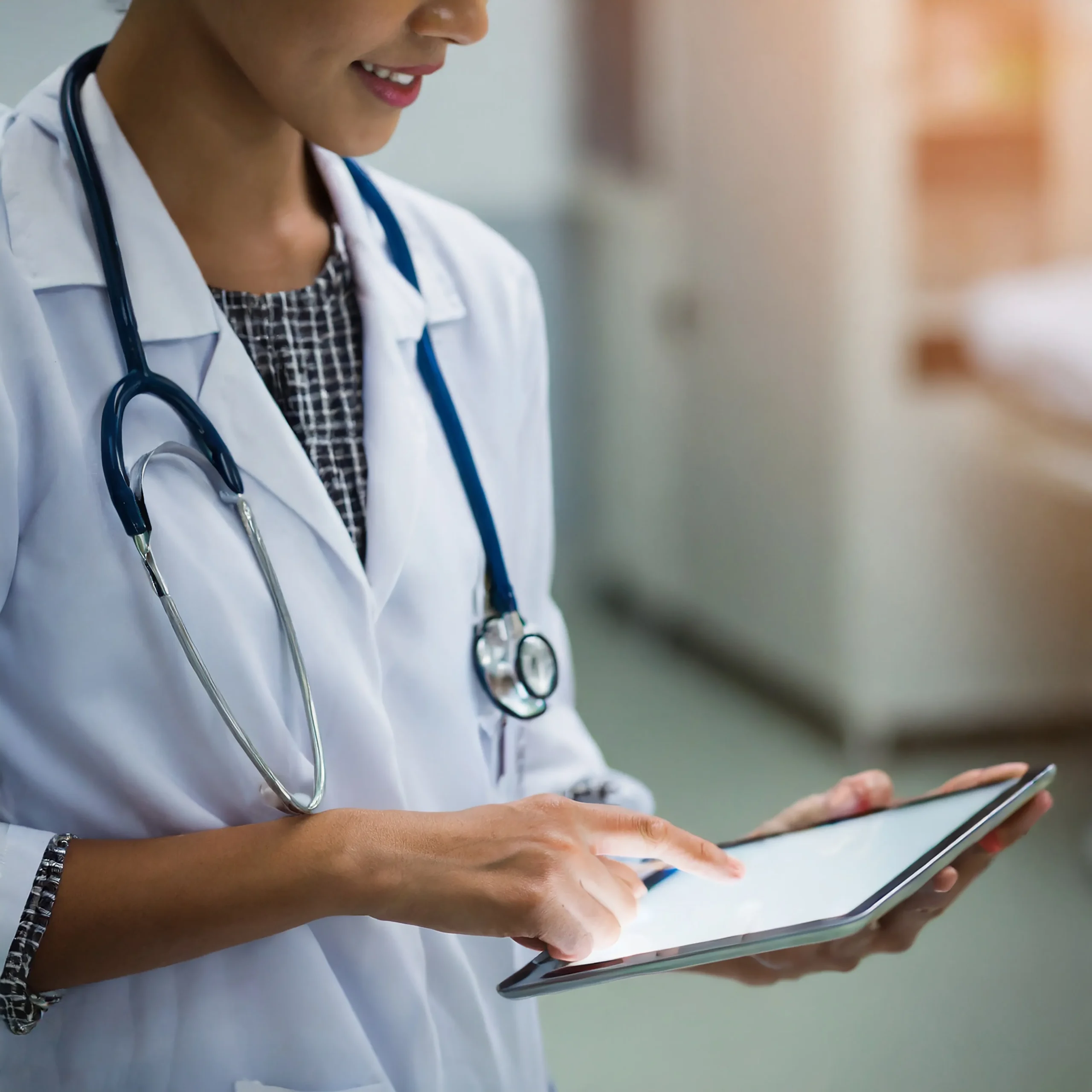 A doctor in a white coat using a digital tablet to review data for healthcare vendor screening.