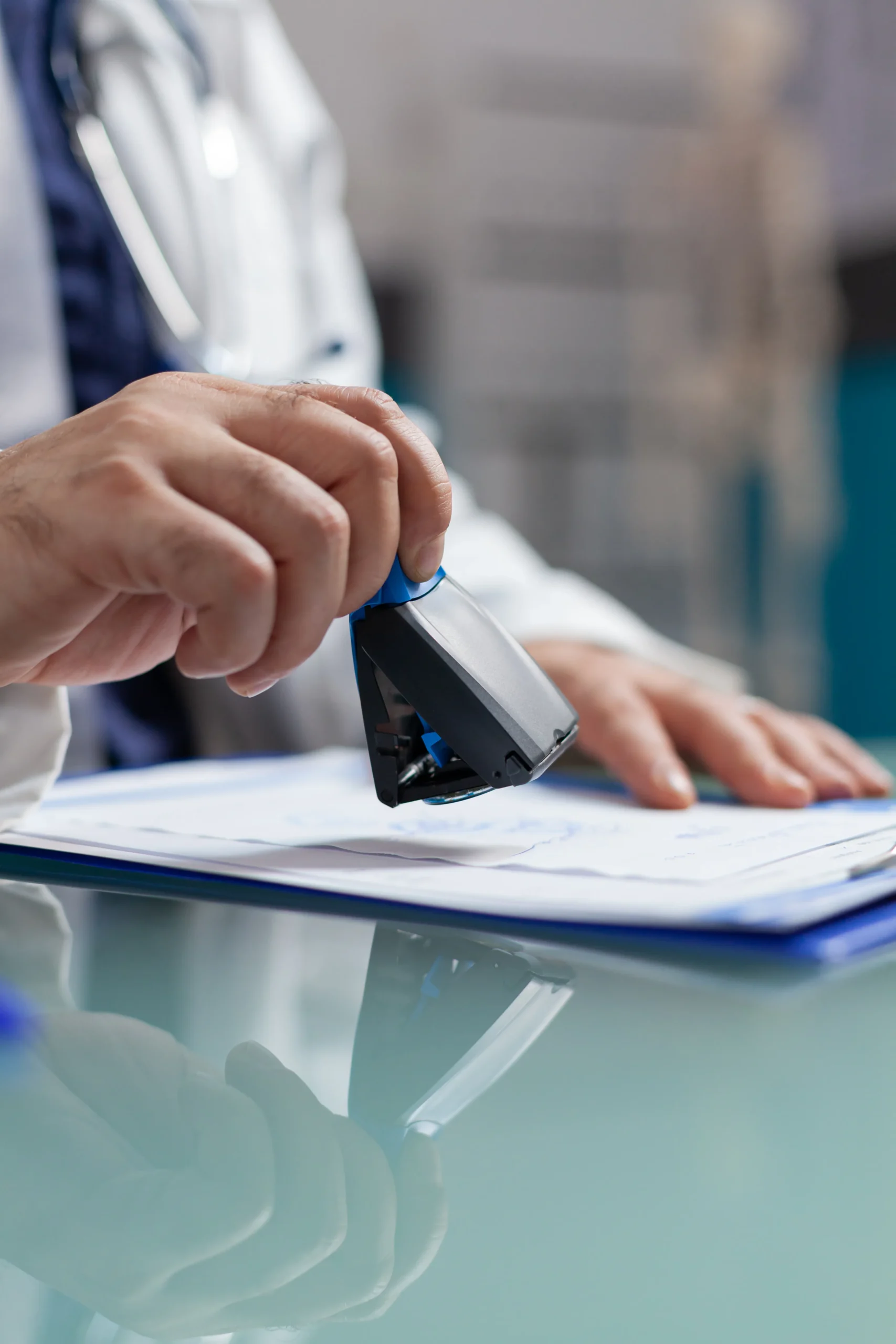 Close-up of a medical administrator stamping a document on a clipboard to confirm verified exclusion monitoring status.