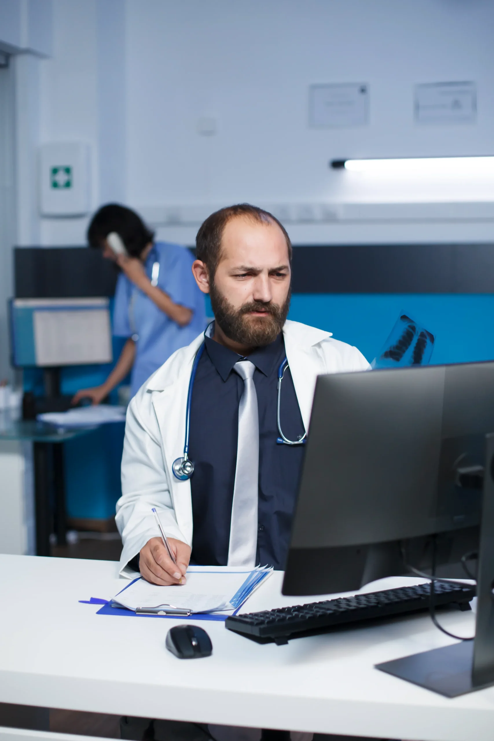 Doctor verifying medical records at a computer terminal as part of routine LEIE screening procedures.