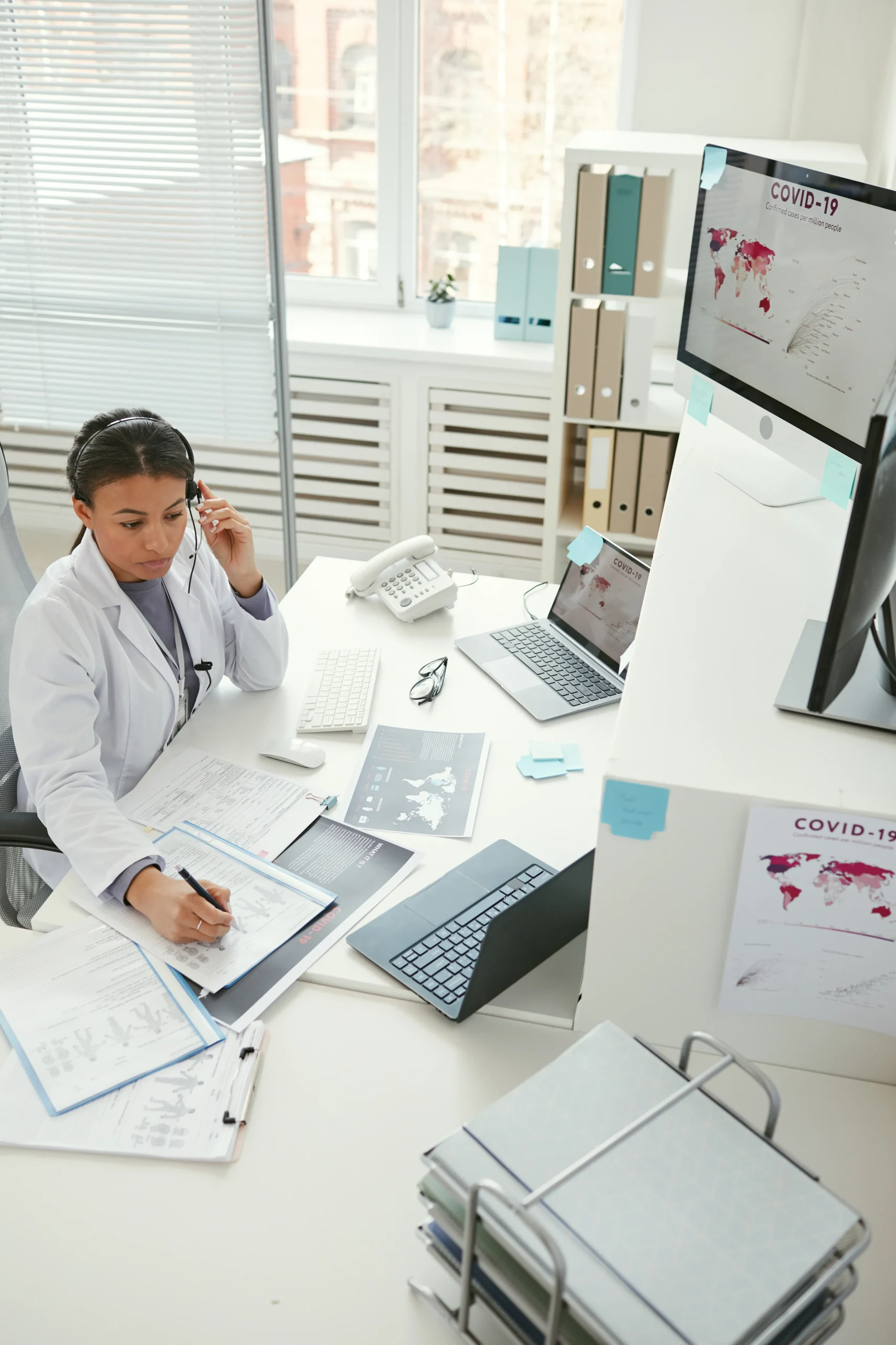 Healthcare worker at a desk managing data for OIG compliance and exclusion screening.