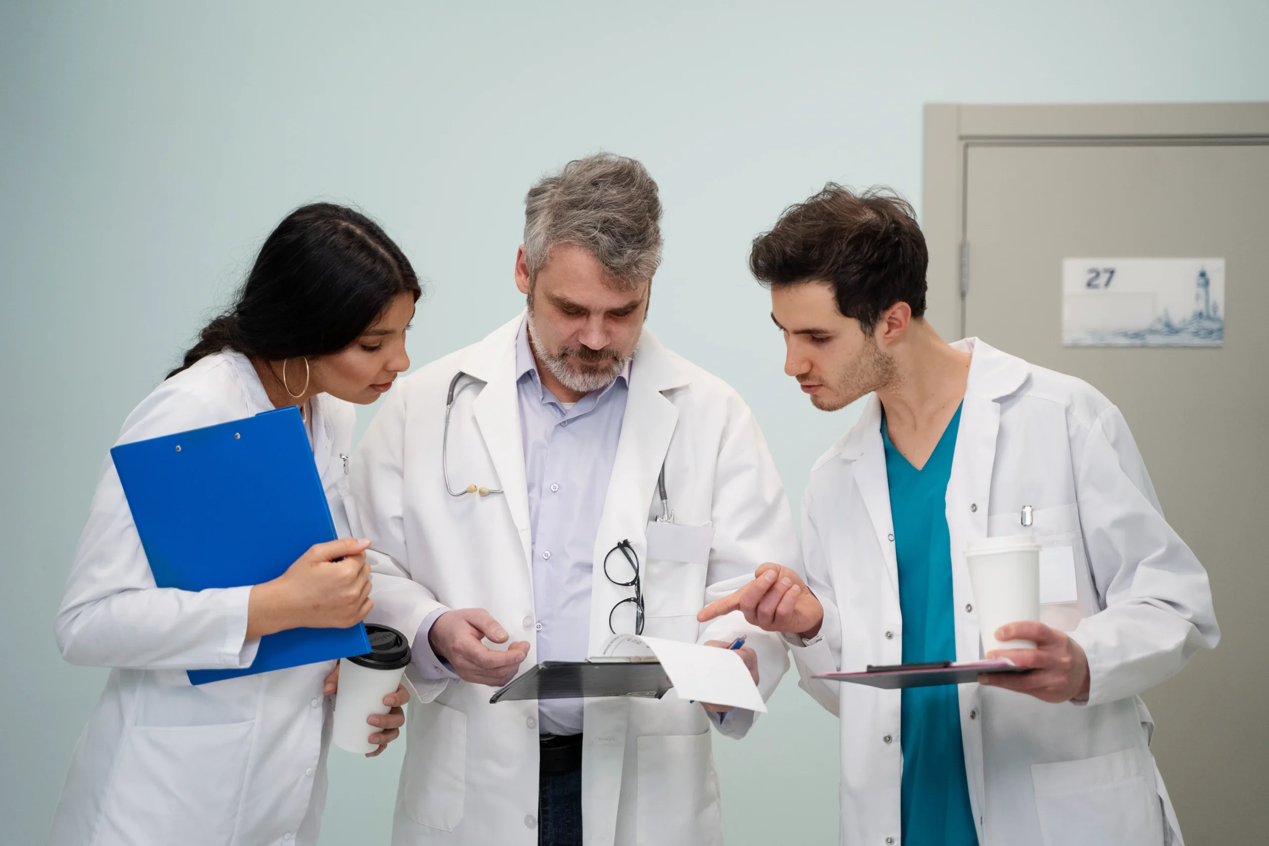 Medical professionals manually reviewing paper documents for compliance screening.