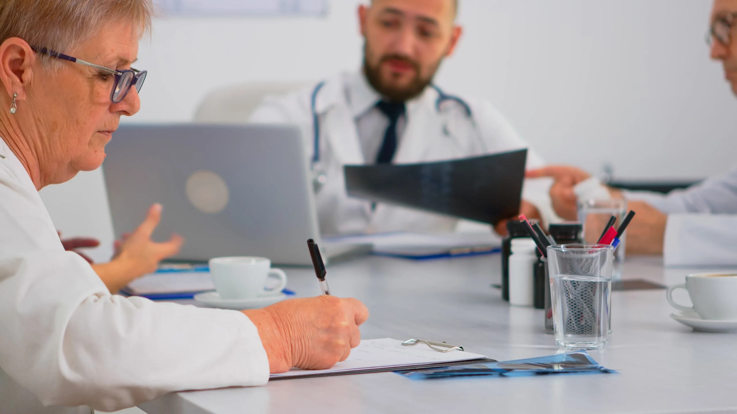 Medical staff reviewing reports in a conference room to streamline compliance management.
