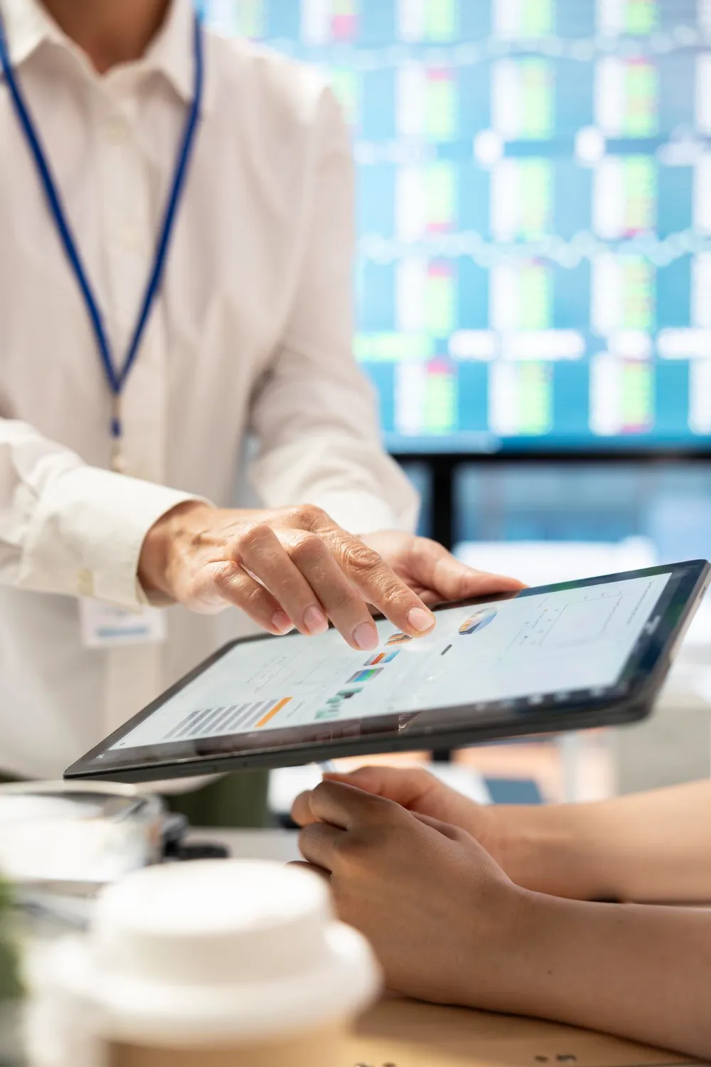 A professional pointing at data dashboard analytics on a tablet screen using compliance screening software.