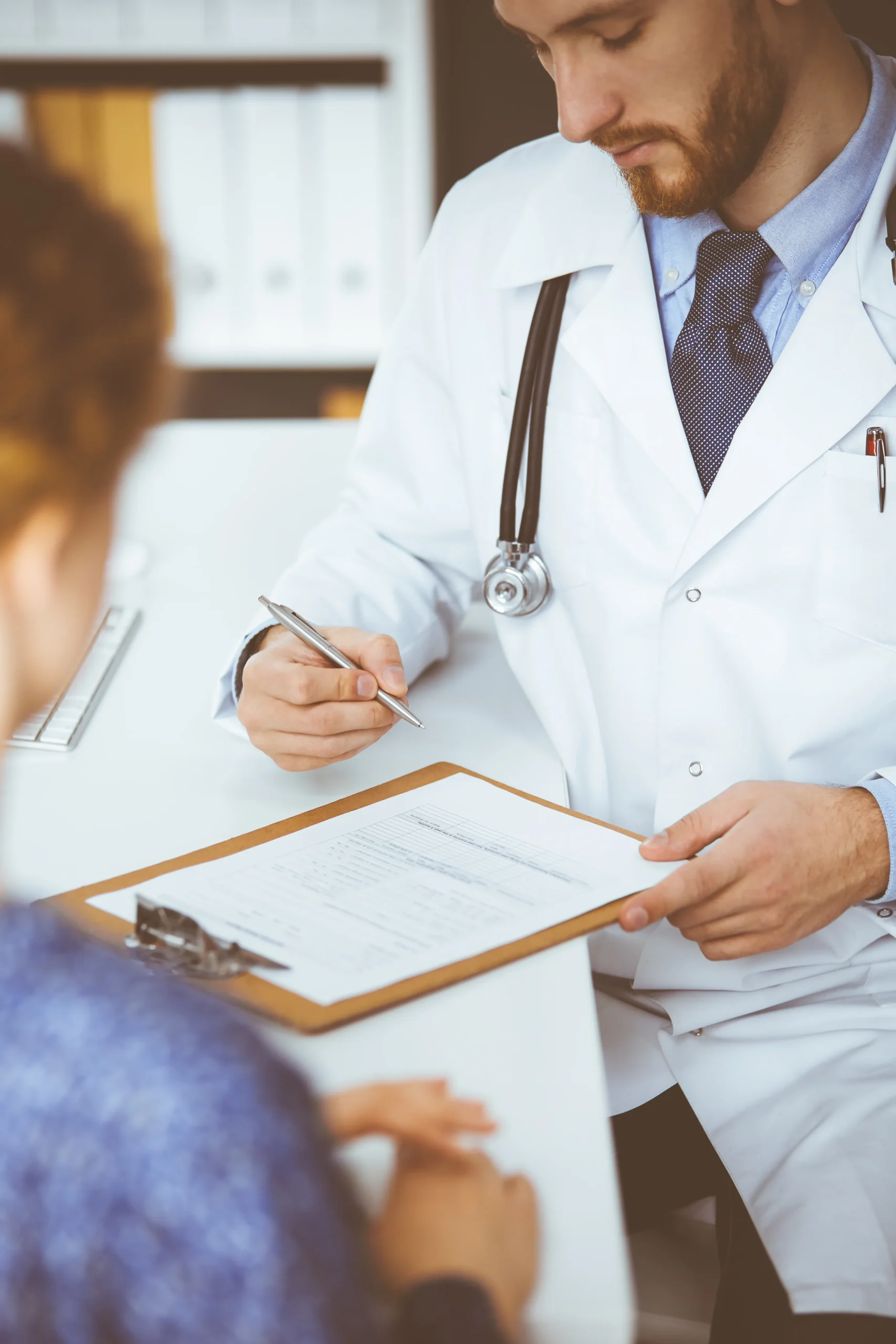 Healthcare professional filling out compliance forms for routine OIG and SAM screening.