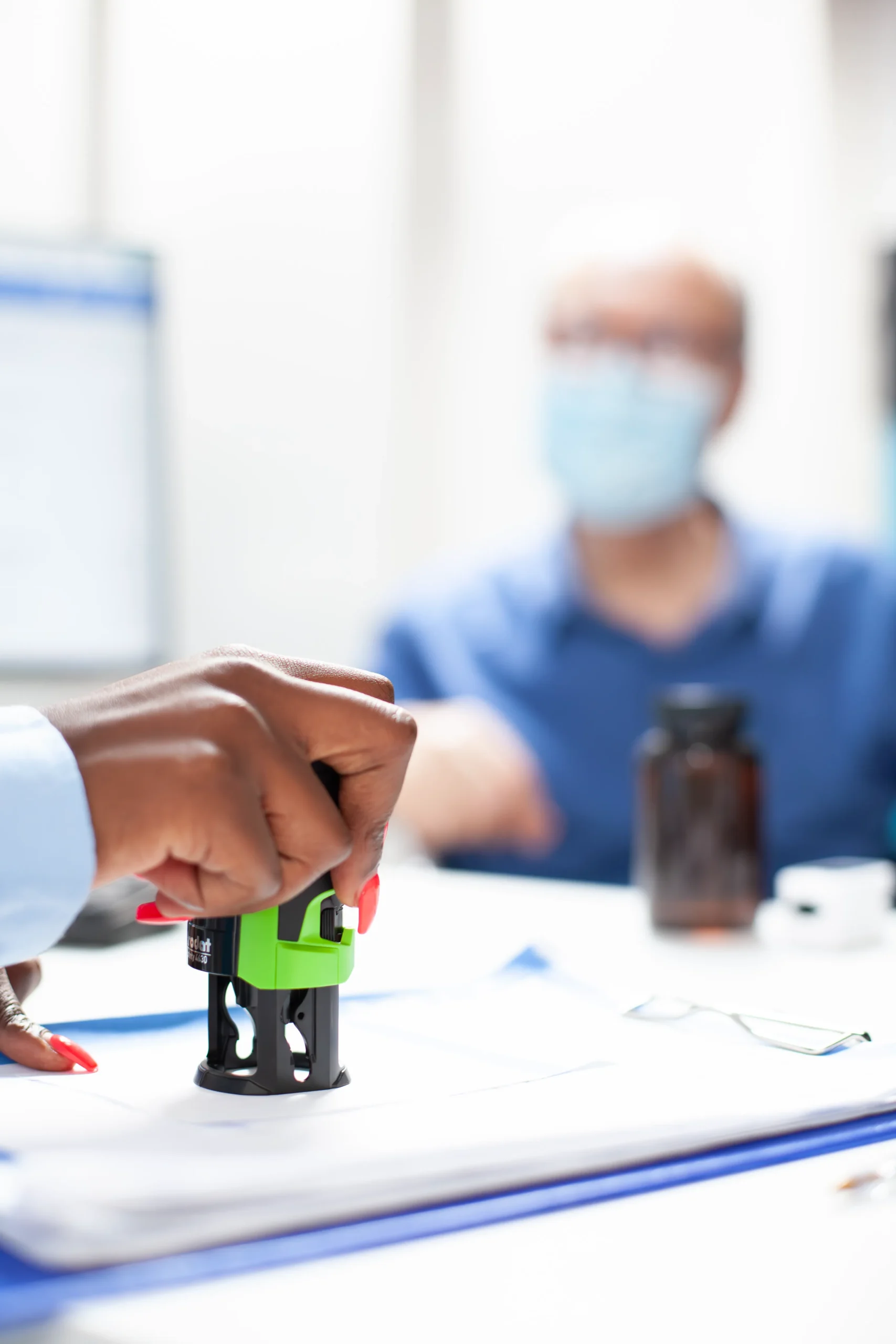 Hand stamping official medical documentation to maintain administrative oversight using healthcare compliance software.