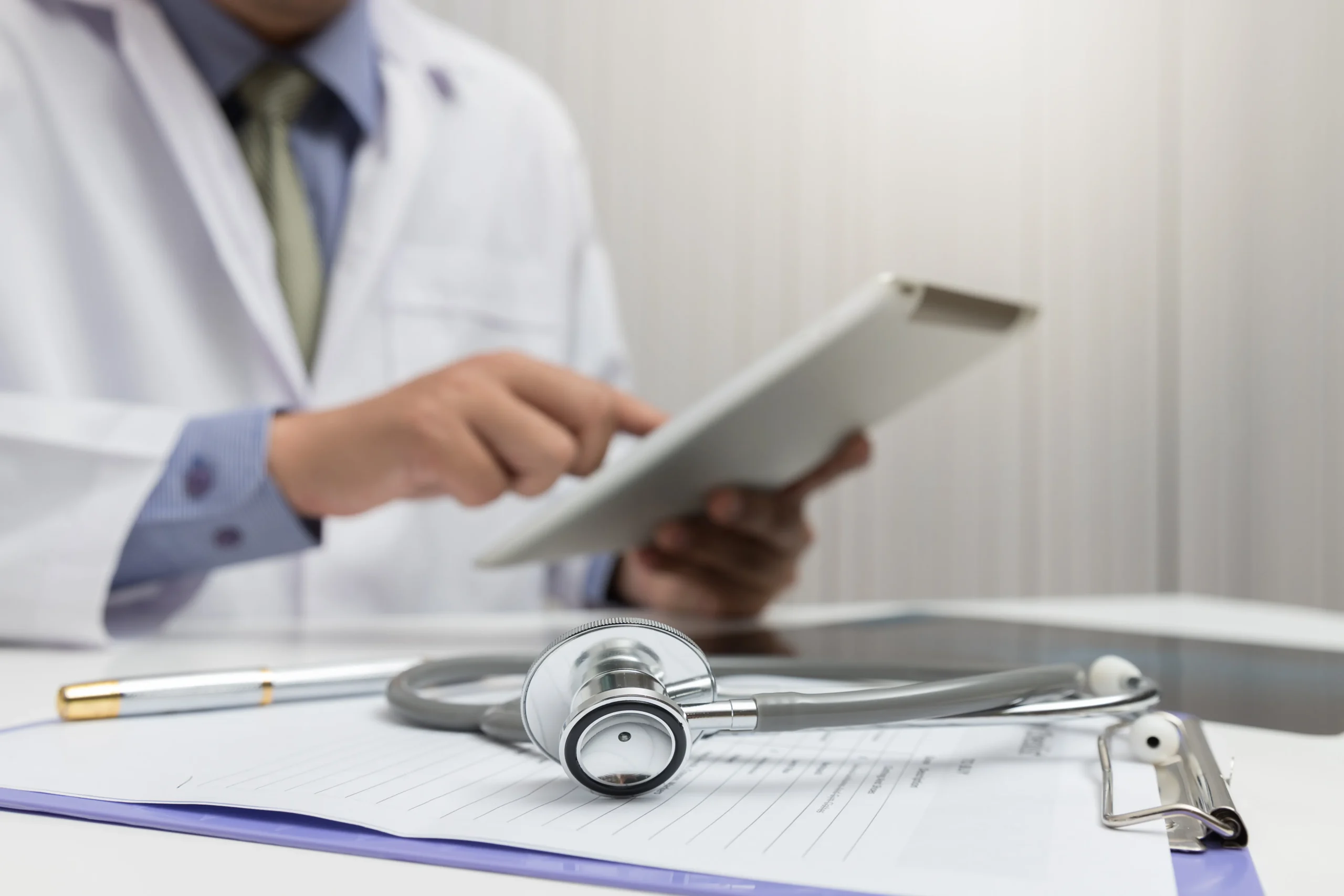Male doctor operating a tablet computer to review provider verification results on Healthcare compliance screening software.