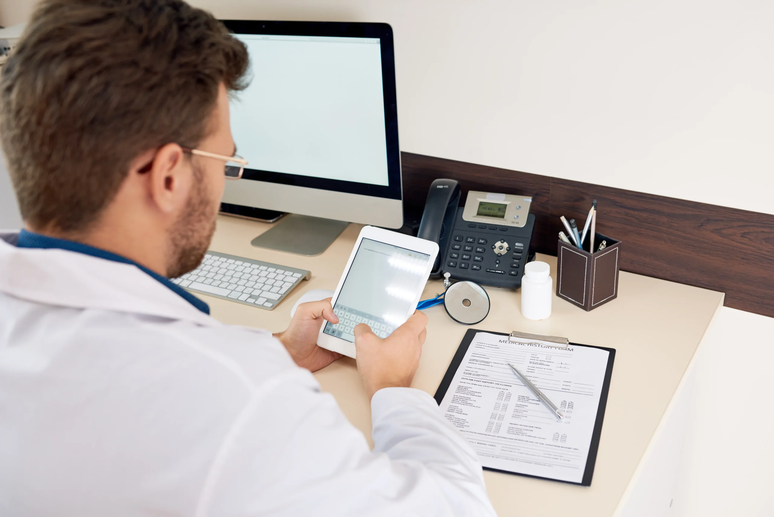 Doctor entering staff credentialing information on a tablet for healthcare exclusion screening.