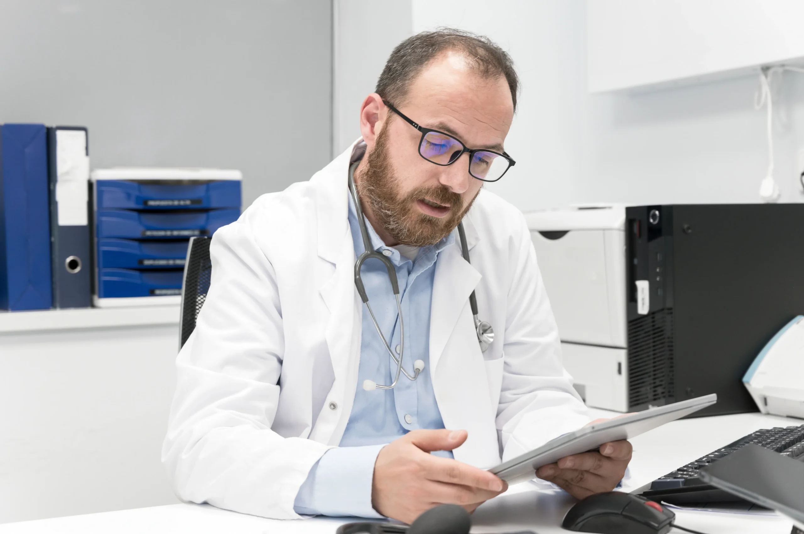 Physician using a tablet to verify practitioner licenses and exclusion compliance screening status.